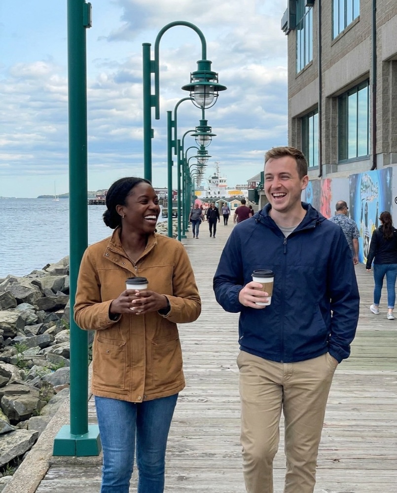 Two friends with coffee walking the Halifax waterfront boardwalk